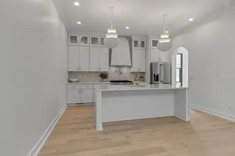 a kitchen with stainless steel appliances granite countertop a refrigerator sink and white cabinets