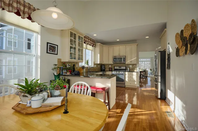 a kitchen with a refrigerator a stove and a dining table with wooden floor