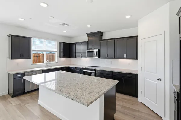 a kitchen with stainless steel appliances granite countertop a sink a stove and a refrigerator