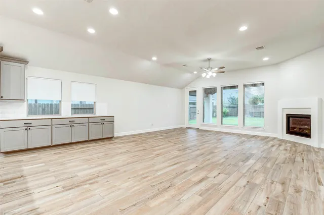 a view of an empty room with a kitchen and a window