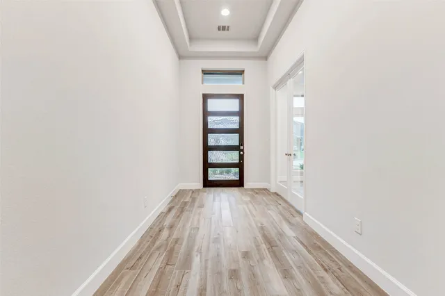 an empty room with wooden floor closet and windows
