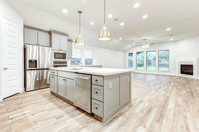 a kitchen with stainless steel appliances granite countertop a stove a refrigerator and a sink with wooden floor