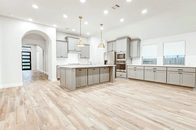 a large kitchen with a large counter top a sink stainless steel appliances and cabinets