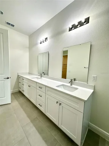 a spacious bathroom with a double vanity sink a mirror and a