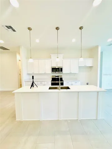 a kitchen with kitchen island granite countertop a sink a counter top space appliances and cabinets