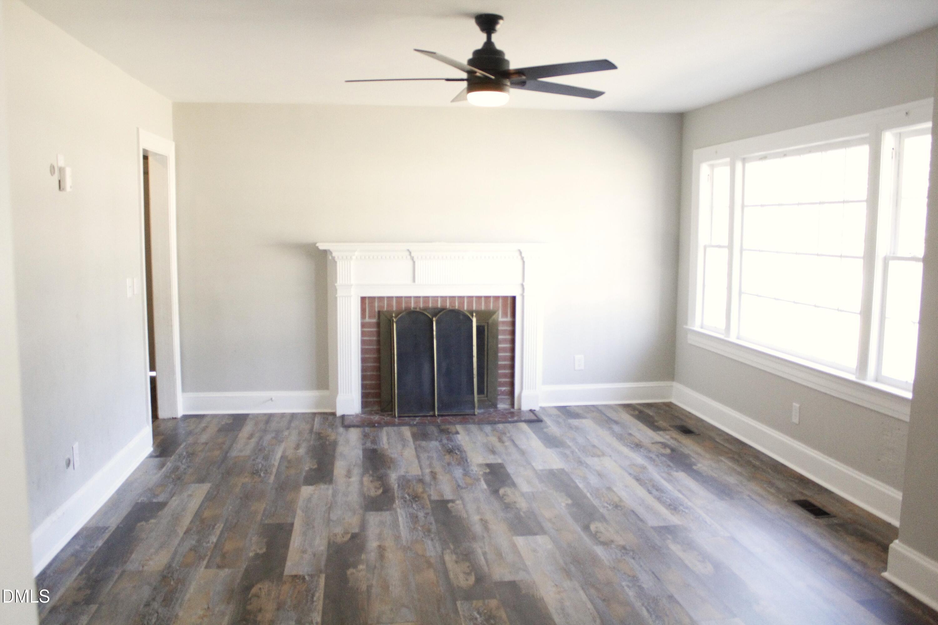 907 Leggett Road Rocky Mount, NC 27801 - Photo 5 of 23 an empty room with wooden floor cabinet and a fireplace