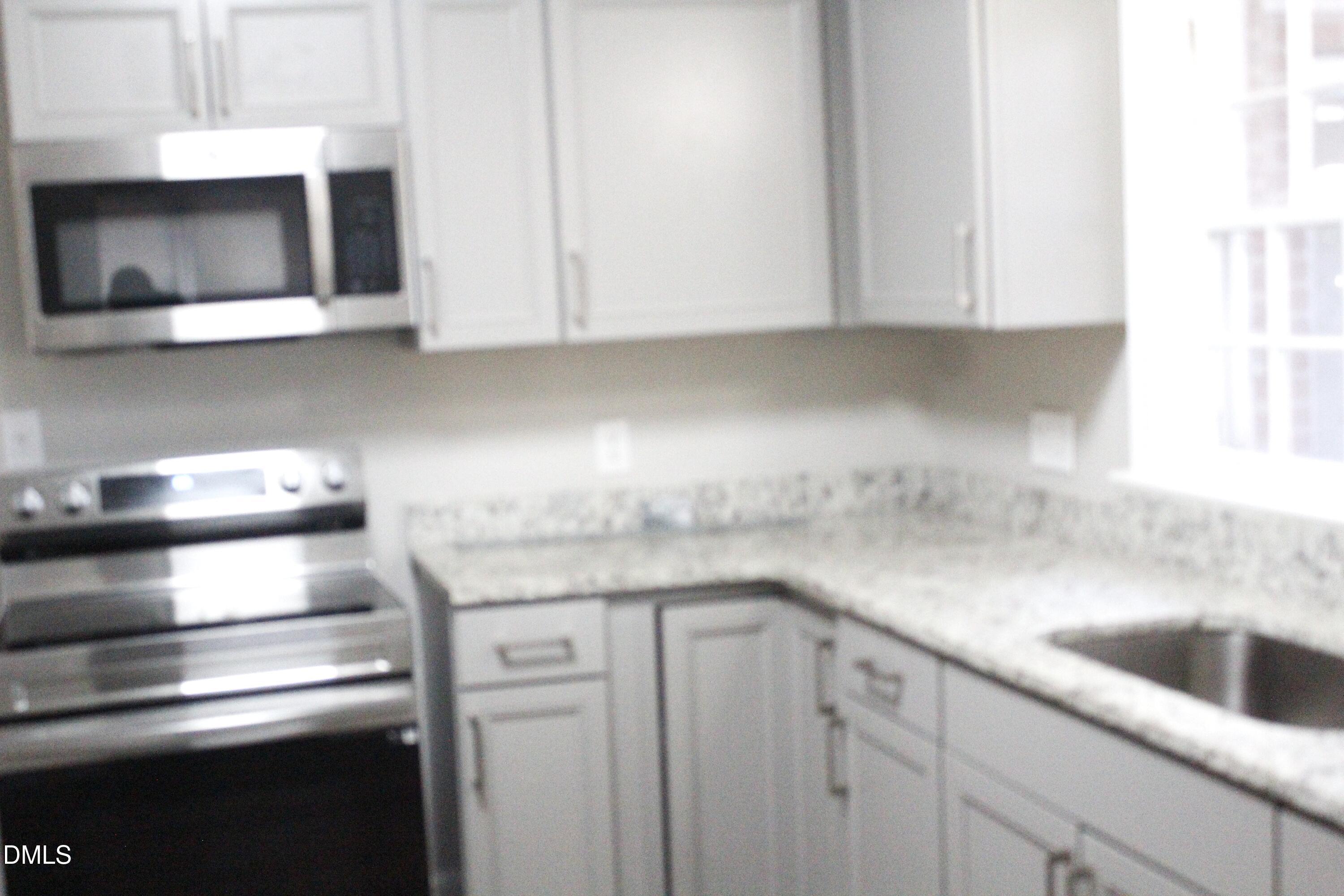 907 Leggett Road Rocky Mount, NC 27801 - Photo 10 of 23 a kitchen with stainless steel appliances granite countertop white cabinets and a stove top oven