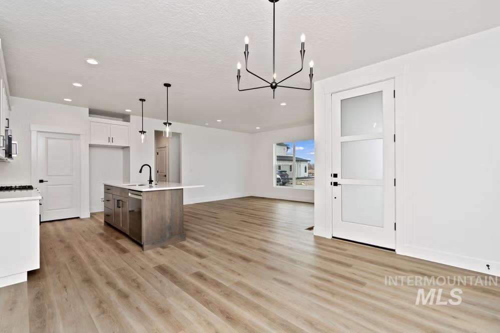744 South Calhoun Lane Star, ID 83669 - Photo 5 of 34 Kitchen featuring white cabinets, pendant lighting, black microwave, a center island with sink, and backsplash