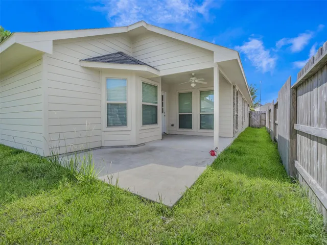 a view of a white house next to a yard with plants