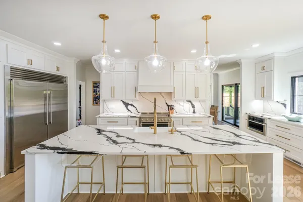 a large kitchen with kitchen island a sink stainless steel appliances and a chandelier