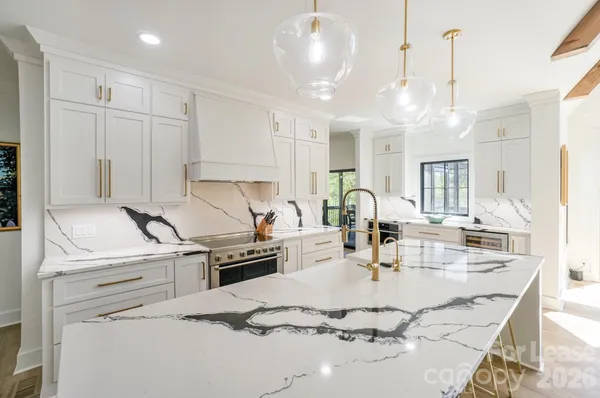 a kitchen with kitchen island a stove a sink a chandelier and dining table