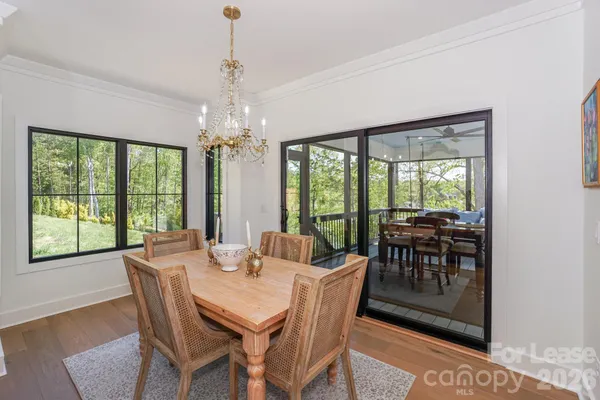 a dining room with furniture a chandelier and large window