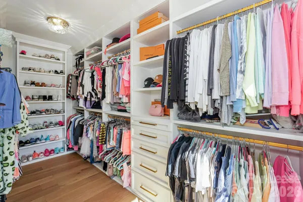 a view of walk in closet with clothes and shoes