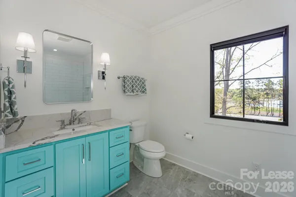 a bathroom with a granite countertop toilet a sink a mirror and a window