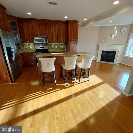 a kitchen with stainless steel appliances kitchen island granite countertop a table chairs sink and cabinets