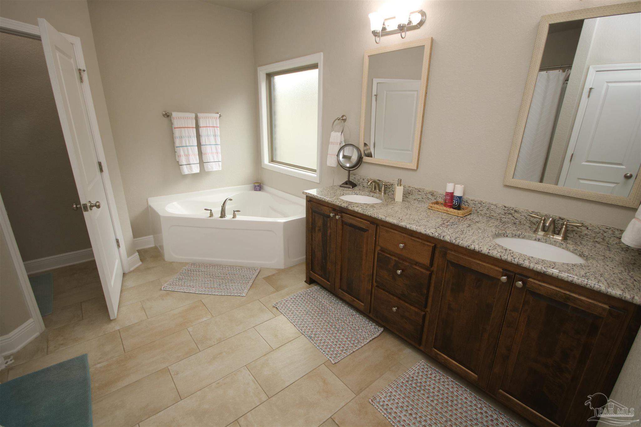 3849 Ranch Road Pace, FL 32571 - Photo 30 of 56 a spacious bathroom with a sink double vanity mirror and bathtub