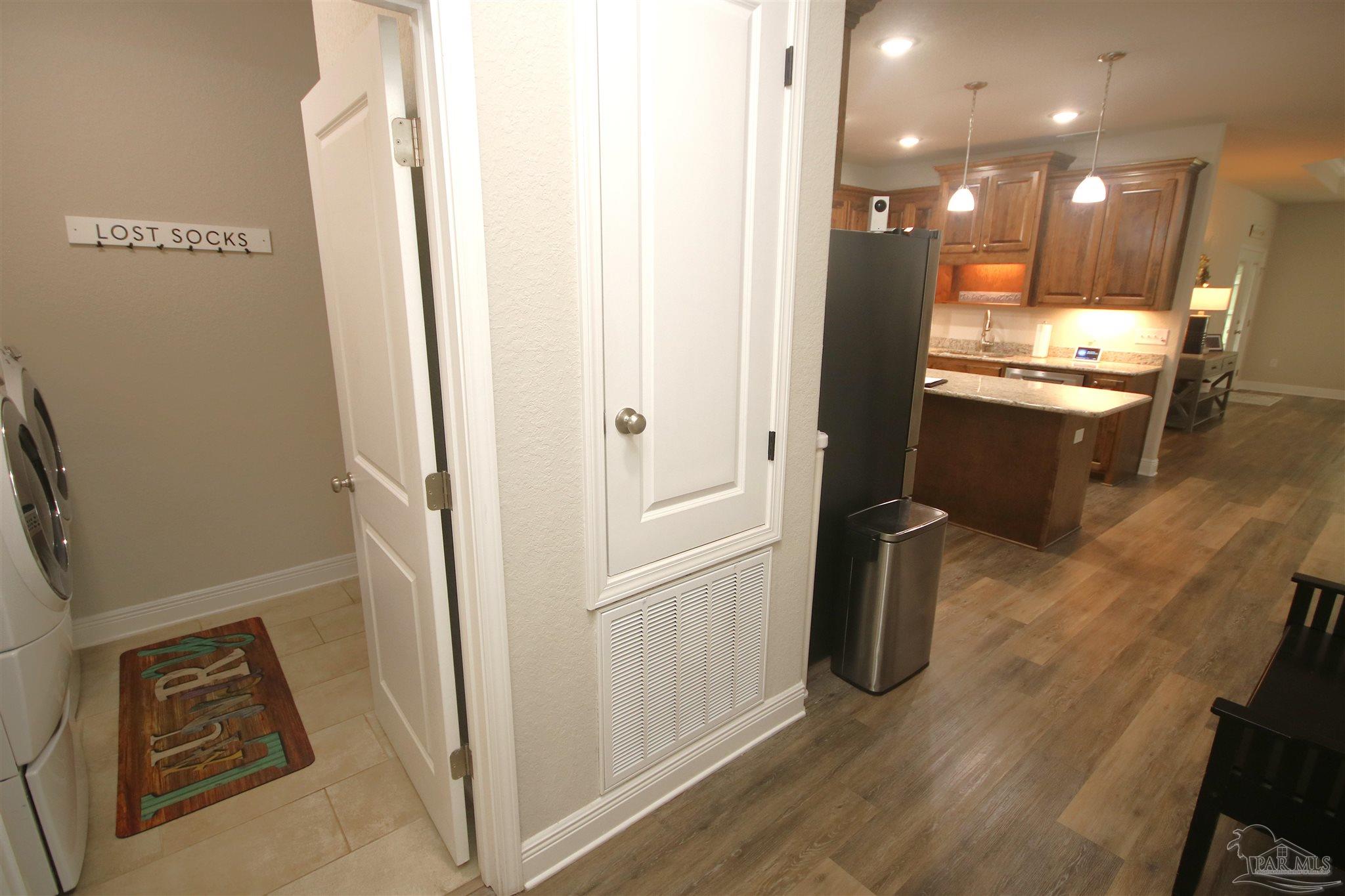 3849 Ranch Road Pace, FL 32571 - Photo 49 of 56 a view of a refrigerator in kitchen and an empty room with wooden floor