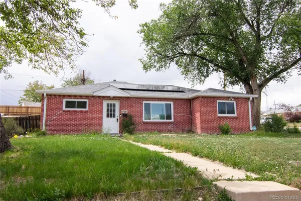 a front view of house with yard and trees in the background