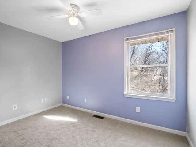 an empty room with a window and a fan
