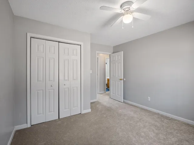 an empty room with closet and a chandelier fan