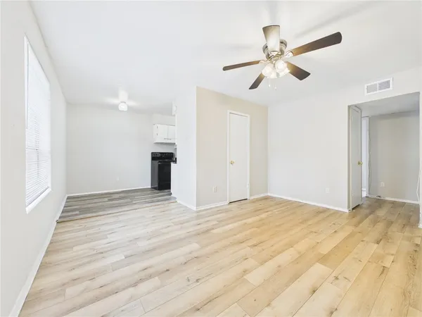 a view of empty room with wooden floor and fan