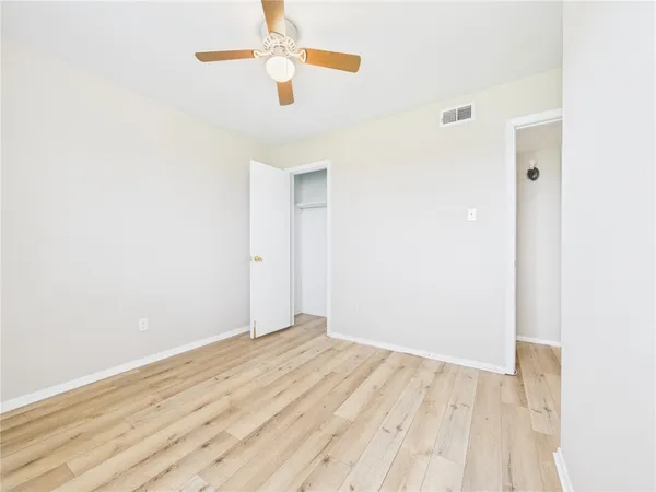 an empty room with wooden floor fan and window