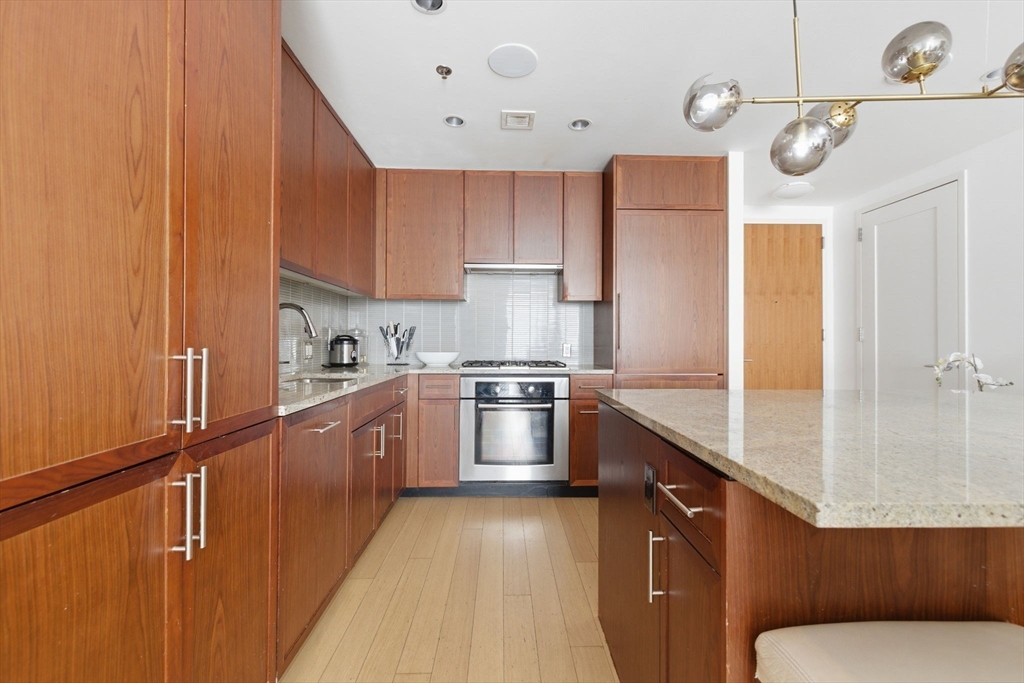 580 Washington Street, Unit 901 Boston, MA 02111 - Photo 11 of 30 a kitchen with stainless steel appliances granite countertop a sink a stove and a refrigerator