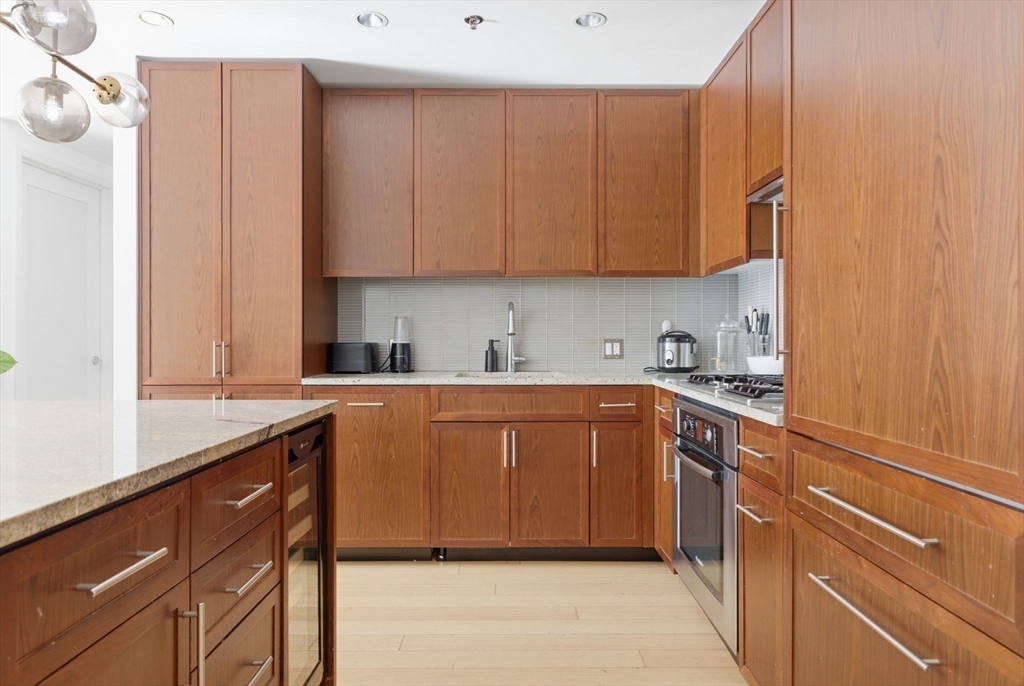 580 Washington Street, Unit 901 Boston, MA 02111 - Photo 12 of 30 a kitchen with stainless steel appliances granite countertop a sink stove and cabinets