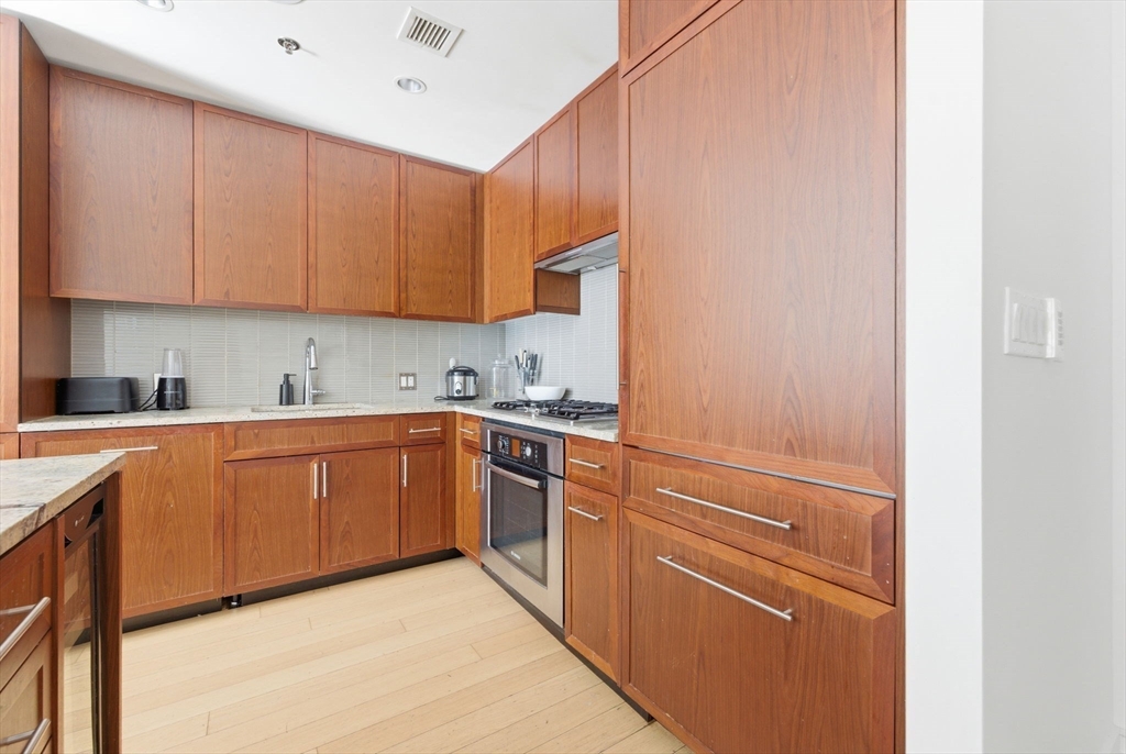580 Washington Street, Unit 901 Boston, MA 02111 - Photo 13 of 30 a kitchen with granite countertop white cabinets and white appliances
