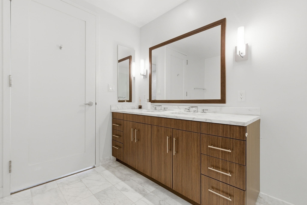 580 Washington Street, Unit 901 Boston, MA 02111 - Photo 17 of 30 a bathroom with a sink vanity and mirror