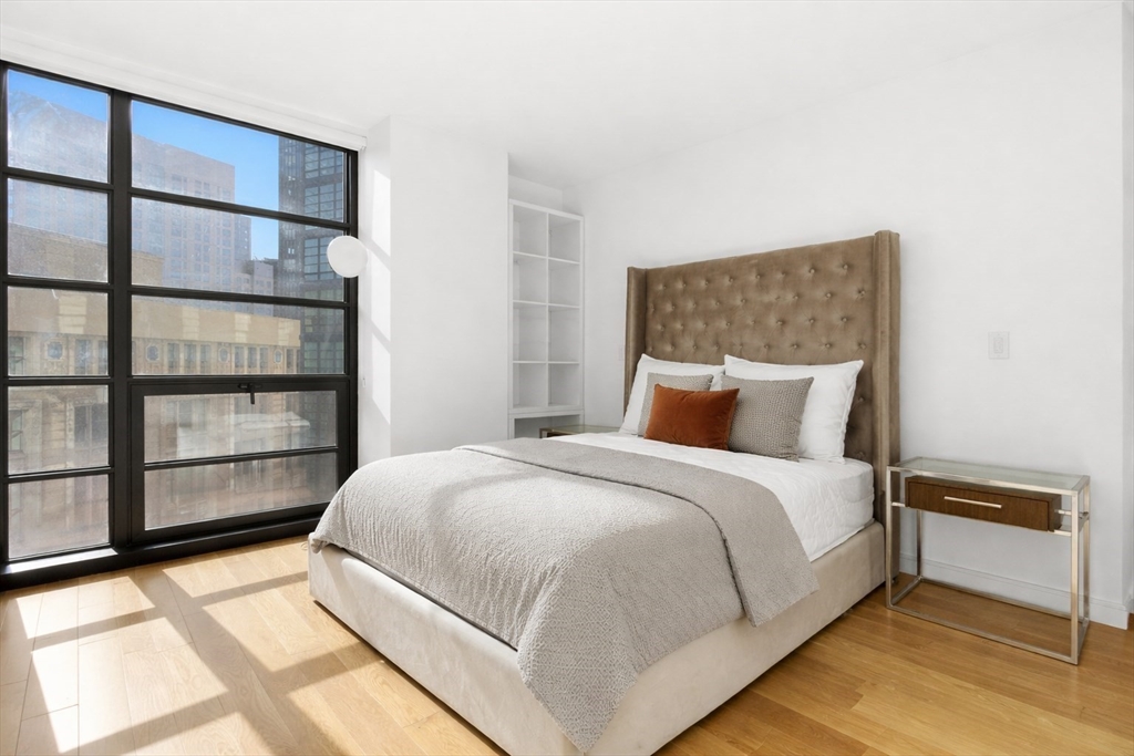 580 Washington Street, Unit 901 Boston, MA 02111 - Photo 18 of 30 a large bed sitting in a bedroom next to a window