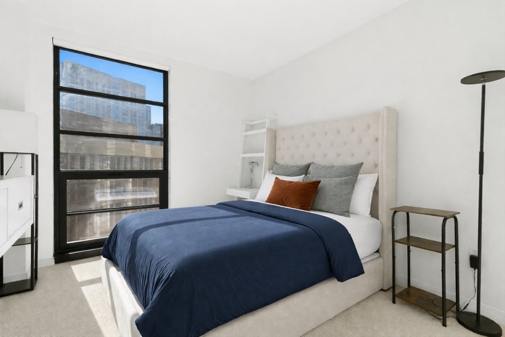 580 Washington Street, Unit 901 Boston, MA 02111 - Photo 20 of 30 a bedroom with a bed and a cabinets