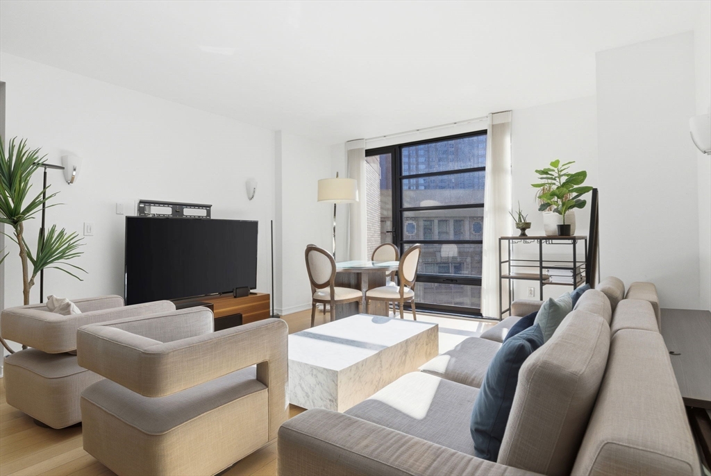580 Washington Street, Unit 901 Boston, MA 02111 - Photo 2 of 30 a living room with furniture a flat screen tv and a potted plant