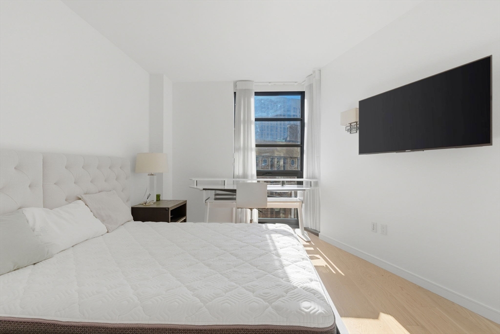 580 Washington Street, Unit 901 Boston, MA 02111 - Photo 23 of 30 a bedroom with a bed and a flat screen tv
