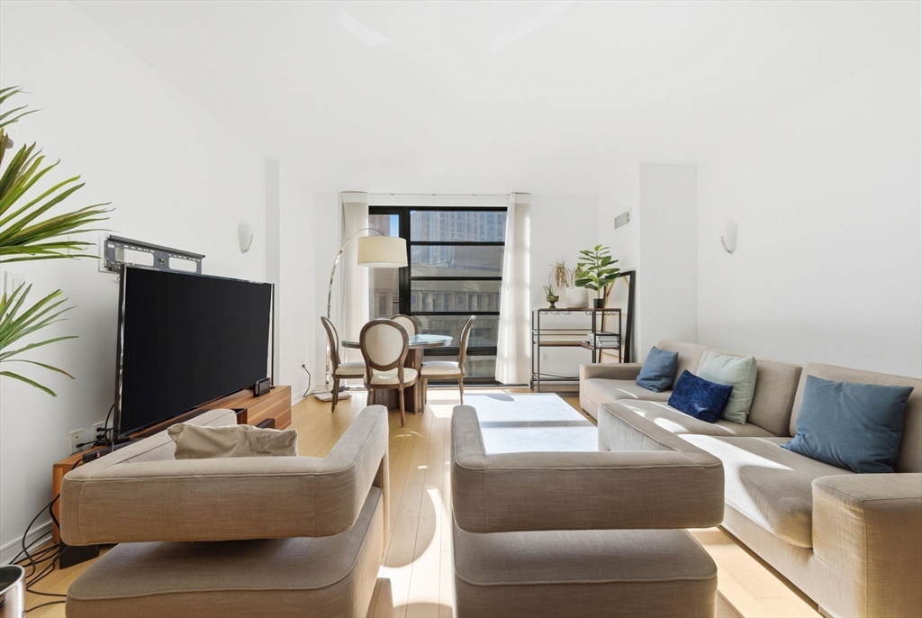 580 Washington Street, Unit 901 Boston, MA 02111 - Photo 3 of 30 a bedroom with furniture and a flat screen tv