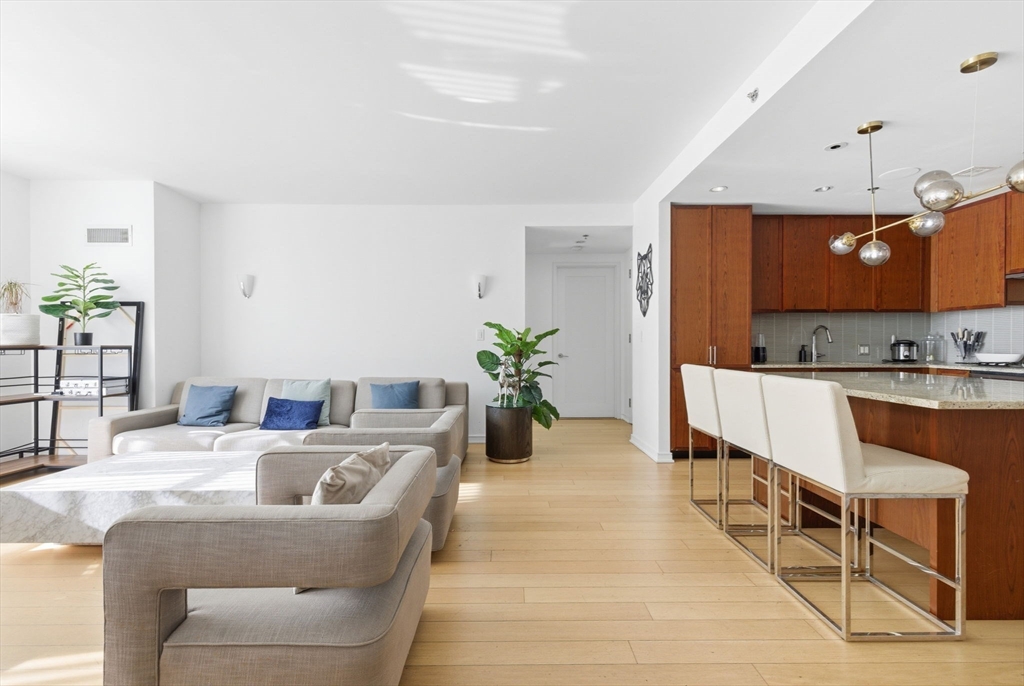 580 Washington Street, Unit 901 Boston, MA 02111 - Photo 4 of 30 a living room with kitchen island furniture and a chandelier