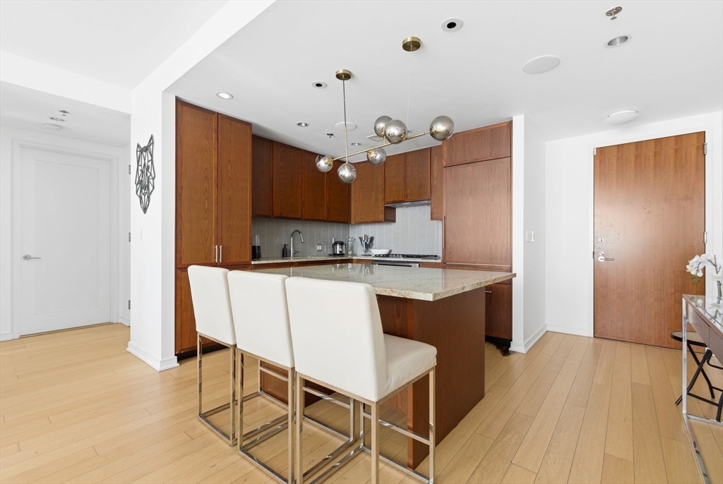 580 Washington Street, Unit 901 Boston, MA 02111 - Photo 7 of 30 a kitchen with a sink cabinets and wooden floor