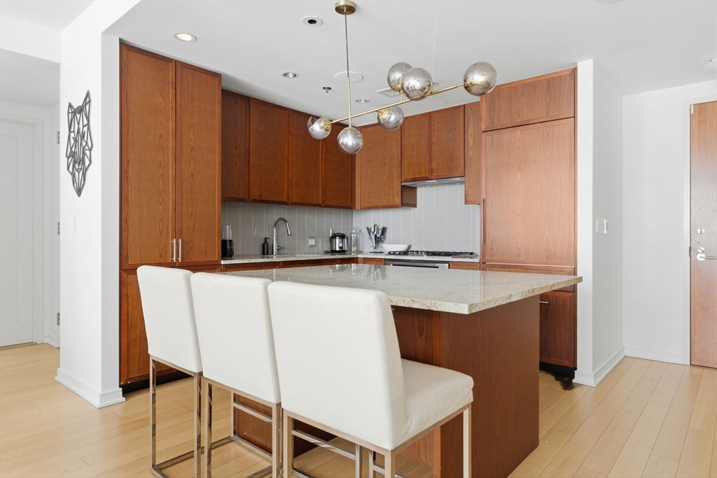 580 Washington Street, Unit 901 Boston, MA 02111 - Photo 8 of 30 a kitchen with stainless steel appliances granite countertop a sink a stove a refrigerator and island with wooden floor