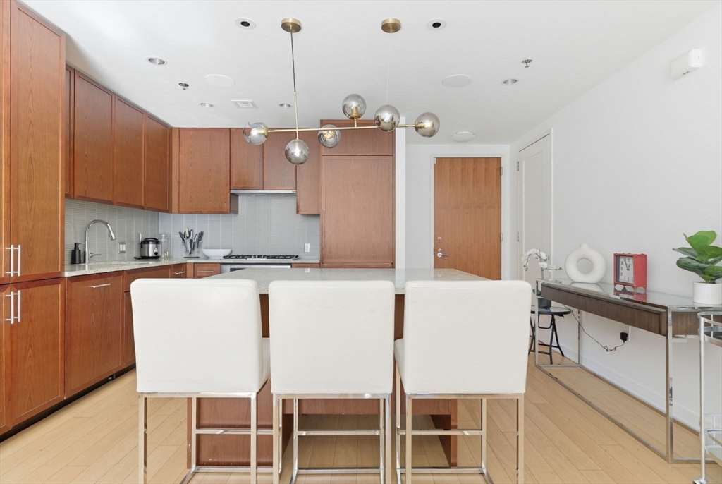 580 Washington Street, Unit 901 Boston, MA 02111 - Photo 9 of 30 a kitchen with a table chairs refrigerator and cabinets