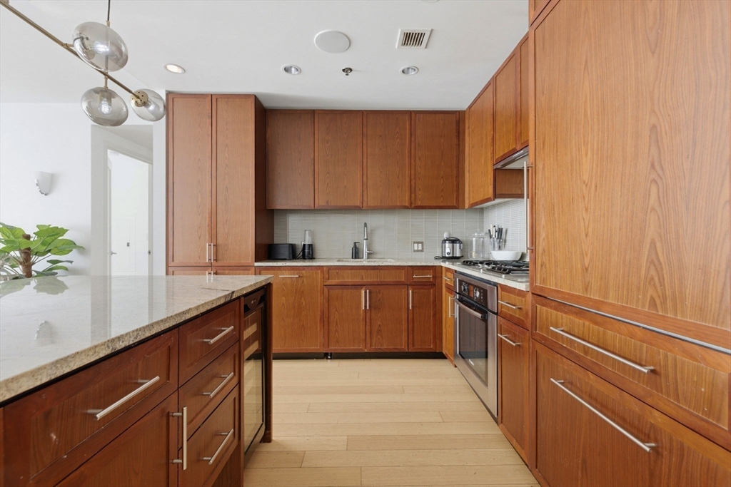 580 Washington Street, Unit 901 Boston, MA 02111 - Photo 10 of 30 a kitchen with stainless steel appliances granite countertop a sink counter space cabinets and a large window