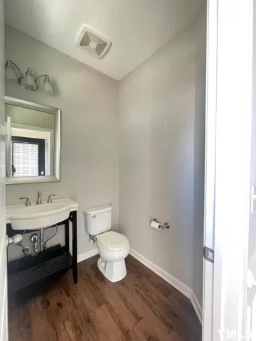 a bathroom with a toilet a sink a mirror and a window