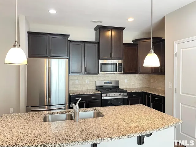a kitchen with stainless steel appliances granite countertop a sink a stove and a refrigerator