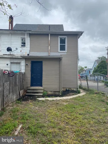 a backyard of a house with table and chairs and wooden fence