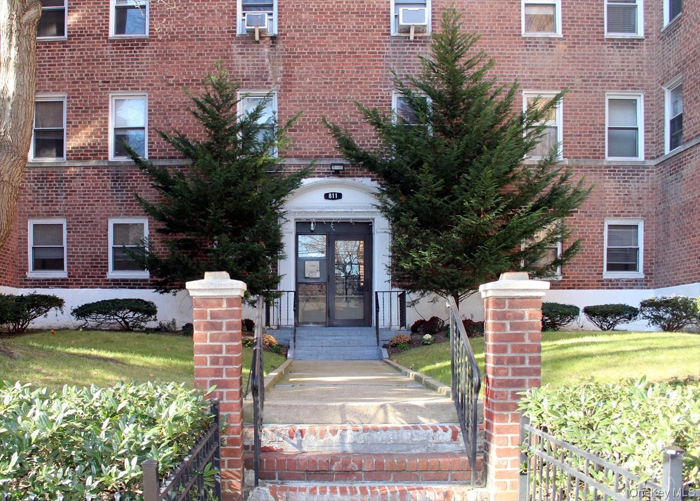 Entrance to property with brick siding and a lawn