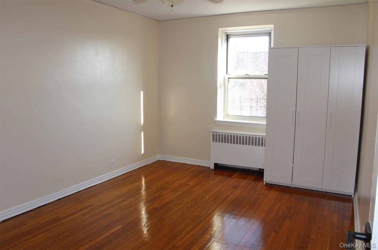 811 Bronx River Road, Unit 5A Yonkers, NY 10708 - Photo 15 of 18 Unfurnished bedroom featuring radiator, dark wood-style floors, and ceiling fan