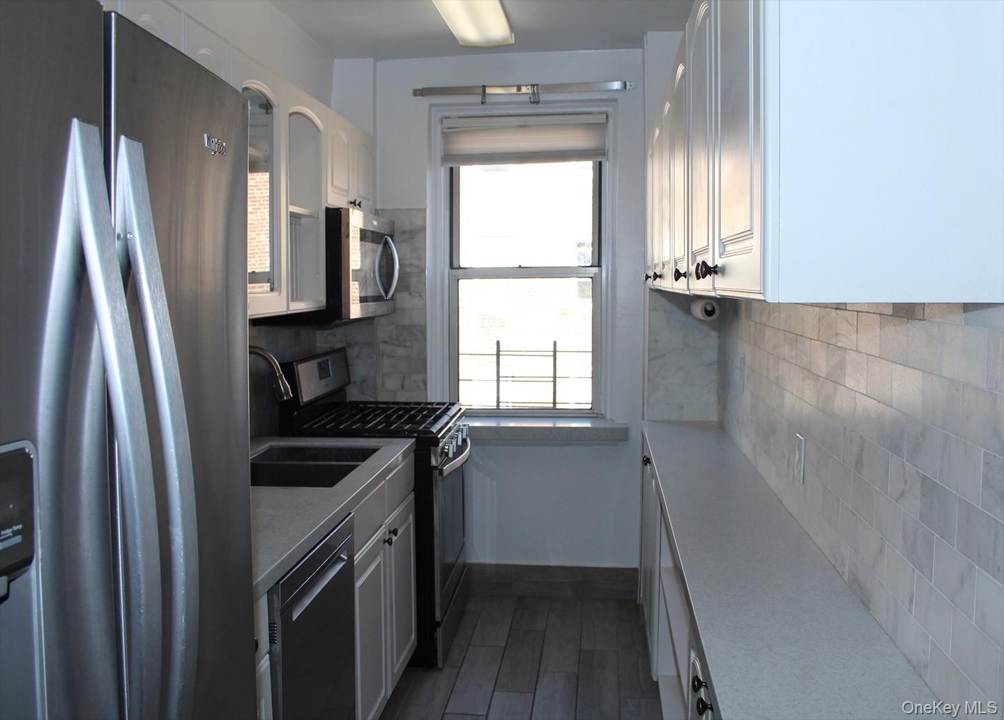 811 Bronx River Road, Unit 5A Yonkers, NY 10708 - Photo 4 of 18 Kitchen featuring appliances with stainless steel finishes, white cabinetry, decorative backsplash, and light countertops
