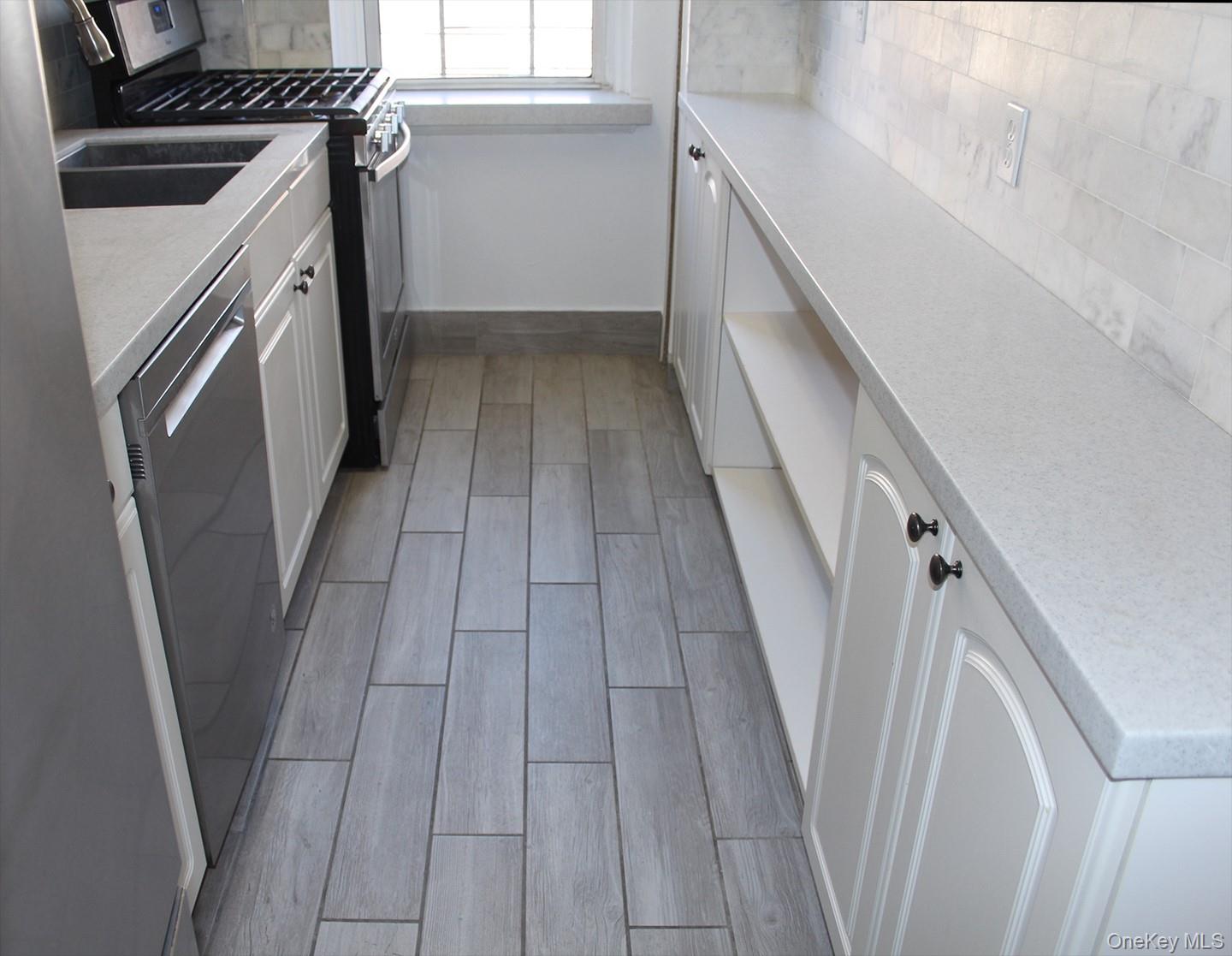811 Bronx River Road, Unit 5A Yonkers, NY 10708 - Photo 5 of 18 Kitchen with decorative backsplash, stainless steel appliances, white cabinets, and wood tiled floors