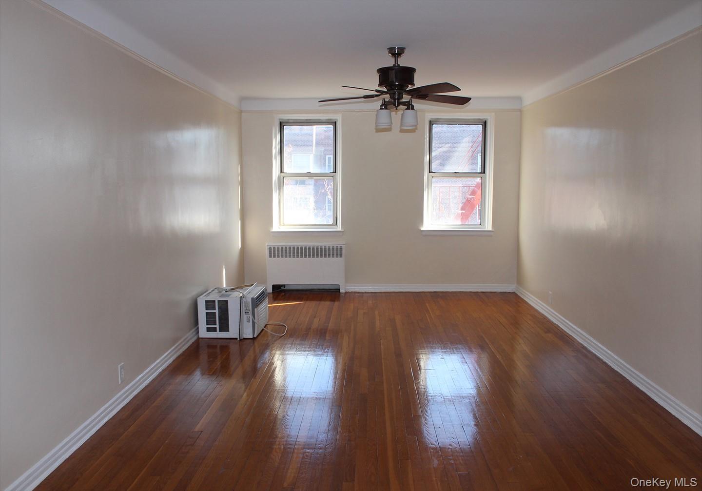 811 Bronx River Road, Unit 5A Yonkers, NY 10708 - Photo 7 of 18 Unfurnished room featuring radiator heating unit, dark wood-style flooring, crown molding, and a ceiling fan