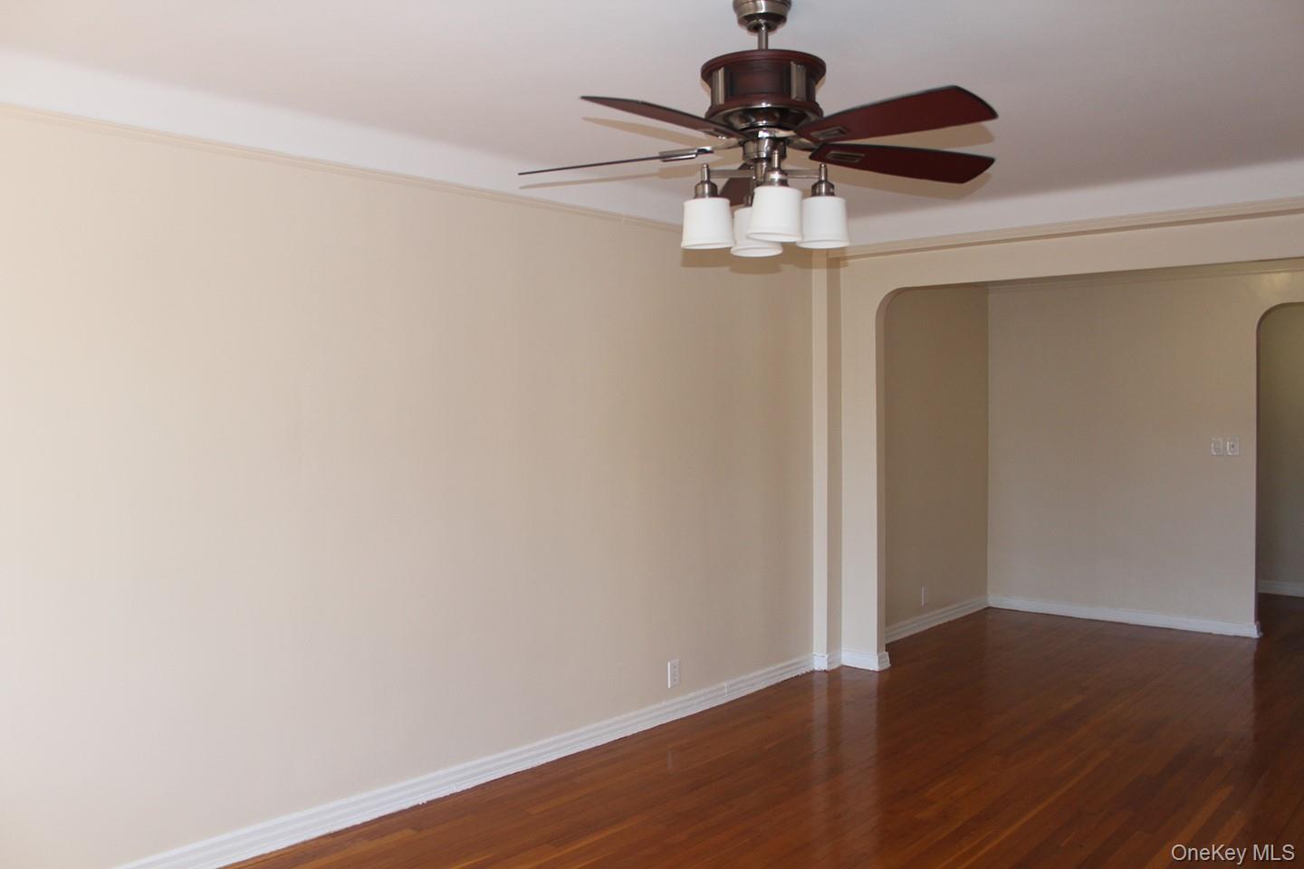 811 Bronx River Road, Unit 5A Yonkers, NY 10708 - Photo 8 of 18 Spare room featuring dark wood-style floors, arched walkways, and ceiling fan