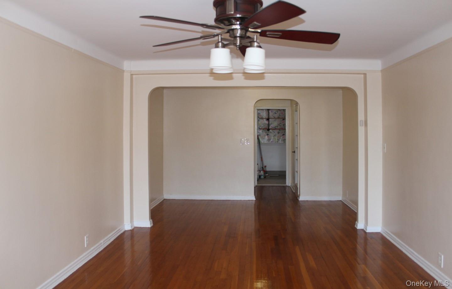 811 Bronx River Road, Unit 5A Yonkers, NY 10708 - Photo 9 of 18 Empty room featuring dark wood-style flooring, arched walkways, and a ceiling fan